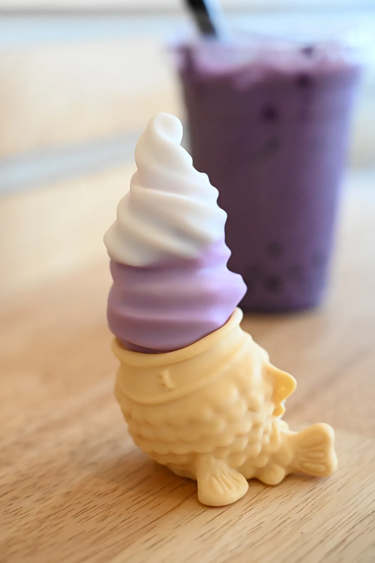 An ube Chai-brator on a wooden table, with a purple drink in the background